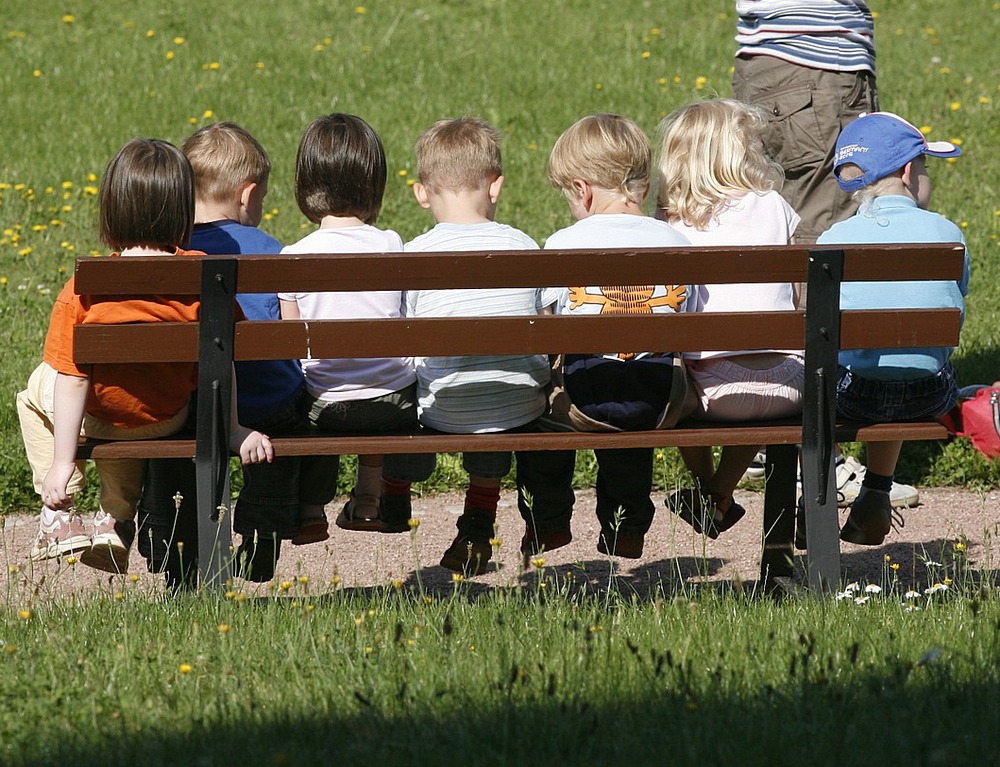 Споры в детском саду. Дети сидят на стульчиках смотрят книгу в детском саду.